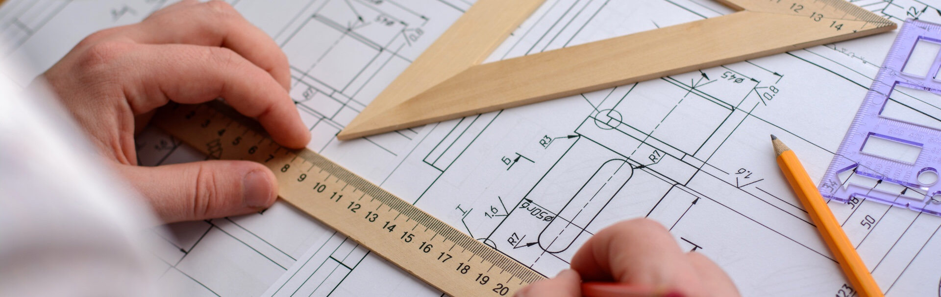 Engineer looking at product blueprints with rulers on top